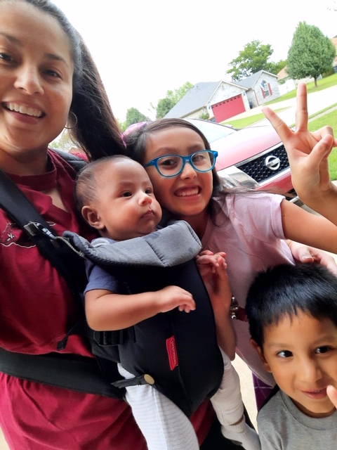 Erika Rodriguez standing with her three children in their neighborhood