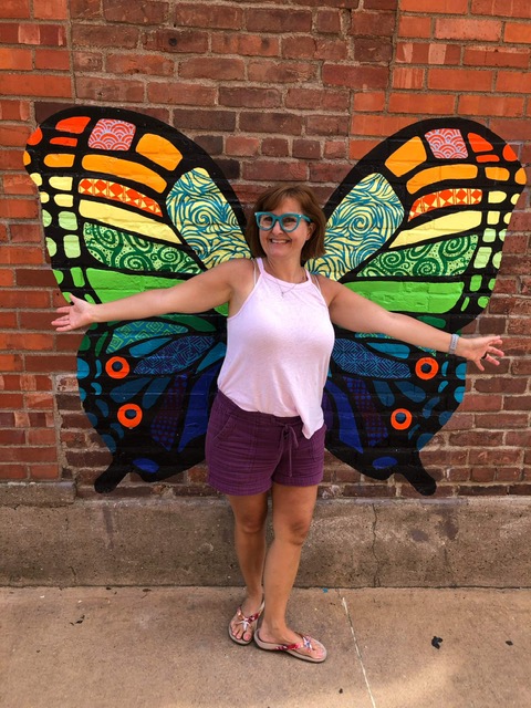 Melanie Hewins in front of butterfly mural.